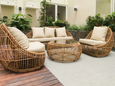 Krem minderli rattan örgü koltuklar ve sehpa, taş duvarlı avluda