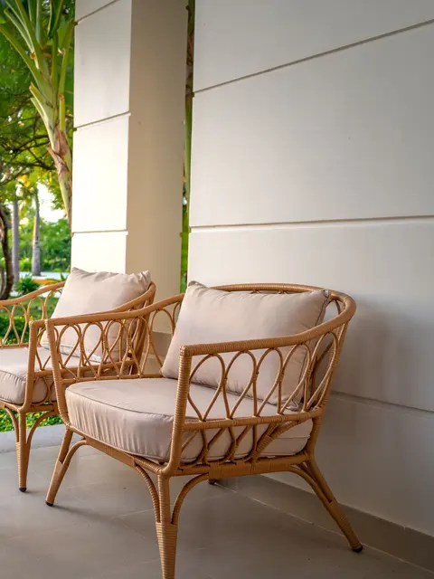 Teras kenarında krem minderli rattan koltuklar ve ahşap sehpa